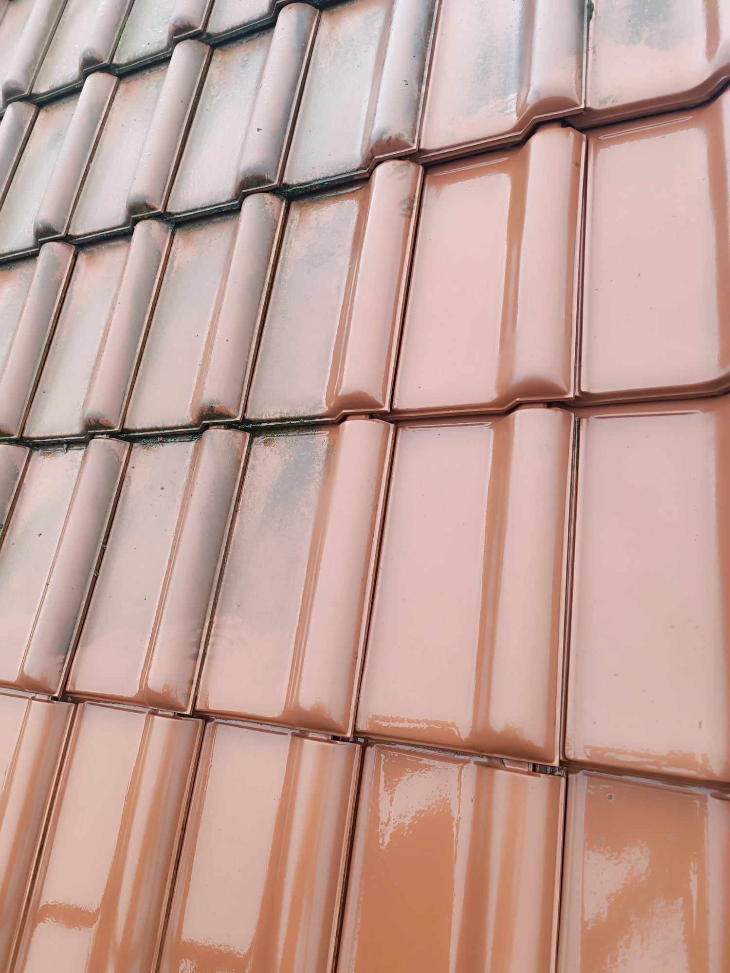 Częściowo umyty dach z ceramicznej dachówki karpiówki w odcieniach brązu, z widoczną różnicą w czystości między umytą a nieumytą częścią dachu.