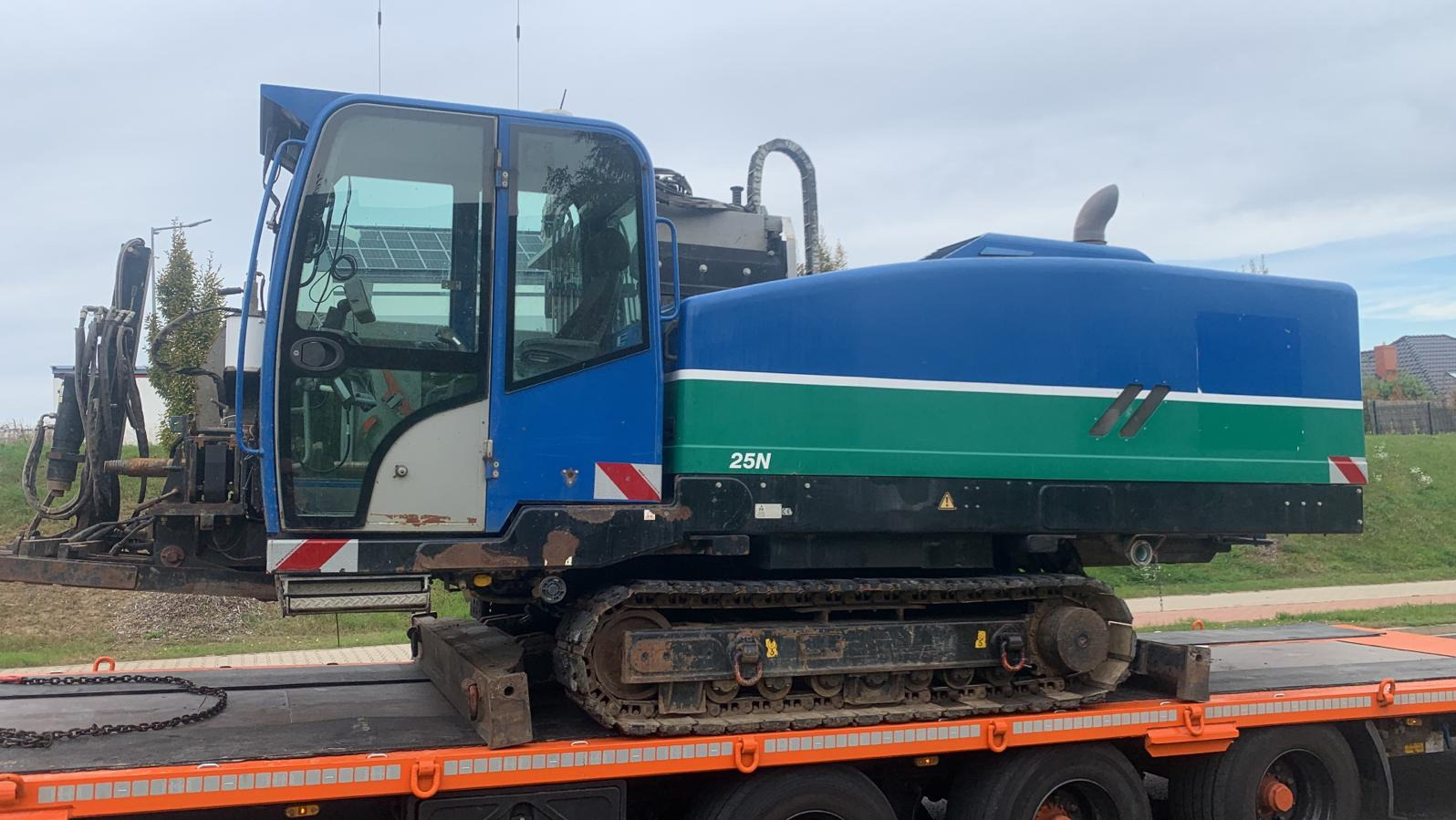 Wiertnica kierunkowa 25N na gąsienicach, transportowana na niskopodwoziowej lawecie, widok z boku, na tle zabudowań.