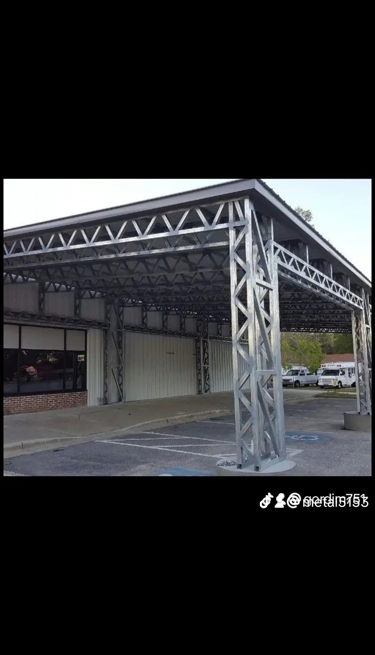 Zadaszenie parkingowe o konstrukcji stalowej, z widocznymi miejscami postojowymi dla osób niepełnosprawnych i pojazdami w tle.