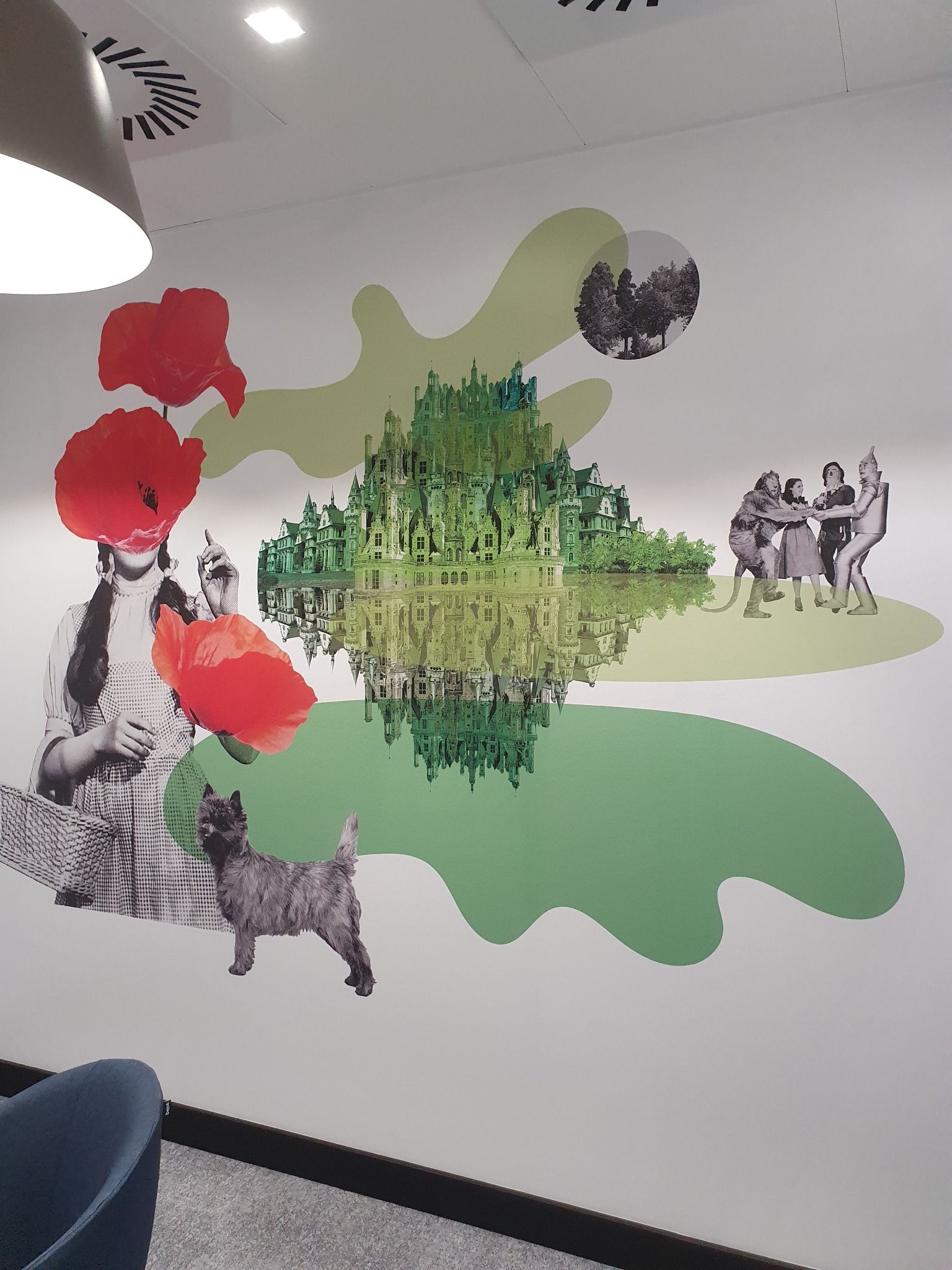 Fototapeta na ścianie przedstawiająca motywy z 'Czarnoksiężnika z Oz': Dorotka z Toto, maki, Szmaragdowe Miasto i drużyna z filmu, całość w stylistyce kolażu z elementami graficznymi.