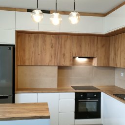 Meble na wymiar Krosno UniGarant PRODUCENT Kuchnie Szafy Garderoby - Nowoczesna kuchnia na wymiar z drewnianymi i białymi frontami, oświetleniem punktowym i srebrną lodówką Samsung.