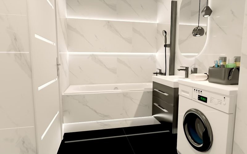 Nowoczesna łazienka z podświetlanymi białymi płytkami imitującymi marmur, czarną armaturą, umywalką z szufladami w kolorze grafitowym i pralką.