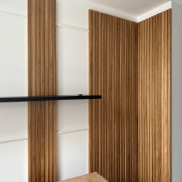 FPHU „MARKUZ” Marcin Kuzara - Dekoracyjne panele ścienne z drewna z pionowymi żłobieniami, połączone z białą ścianą z listwami i czarną półką