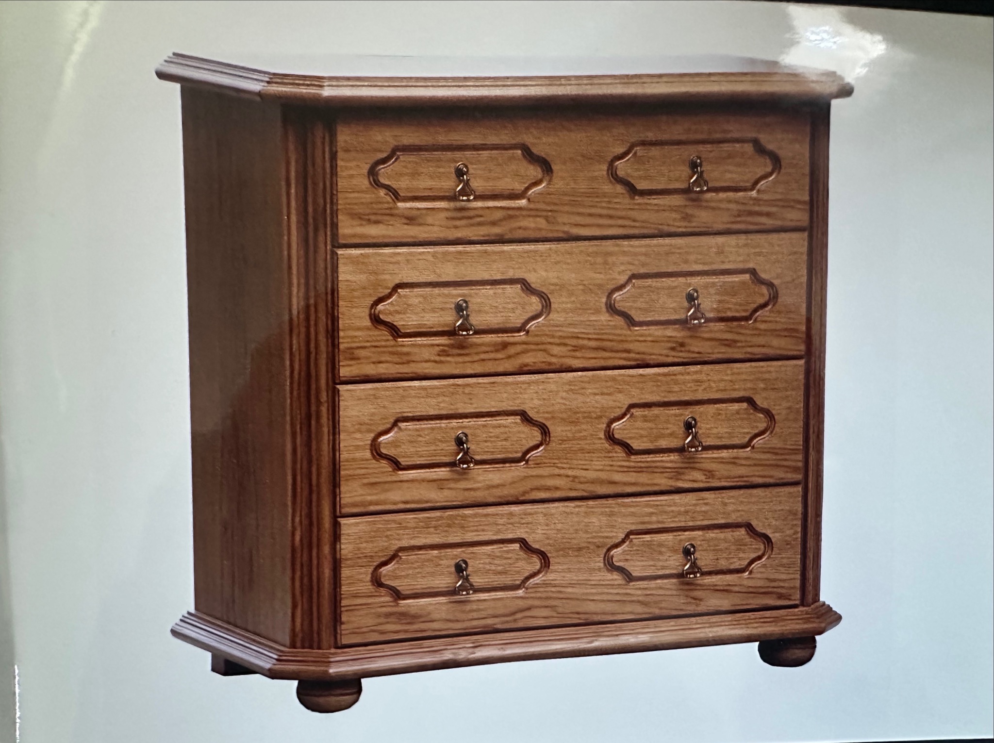 Komoda z czterema szufladami, wykonana z drewna dębowego, z ozdobnymi uchwytami w kształcie kluczy. Klasyczny design z frezowanymi detalami i zaokrąglonym blatem.