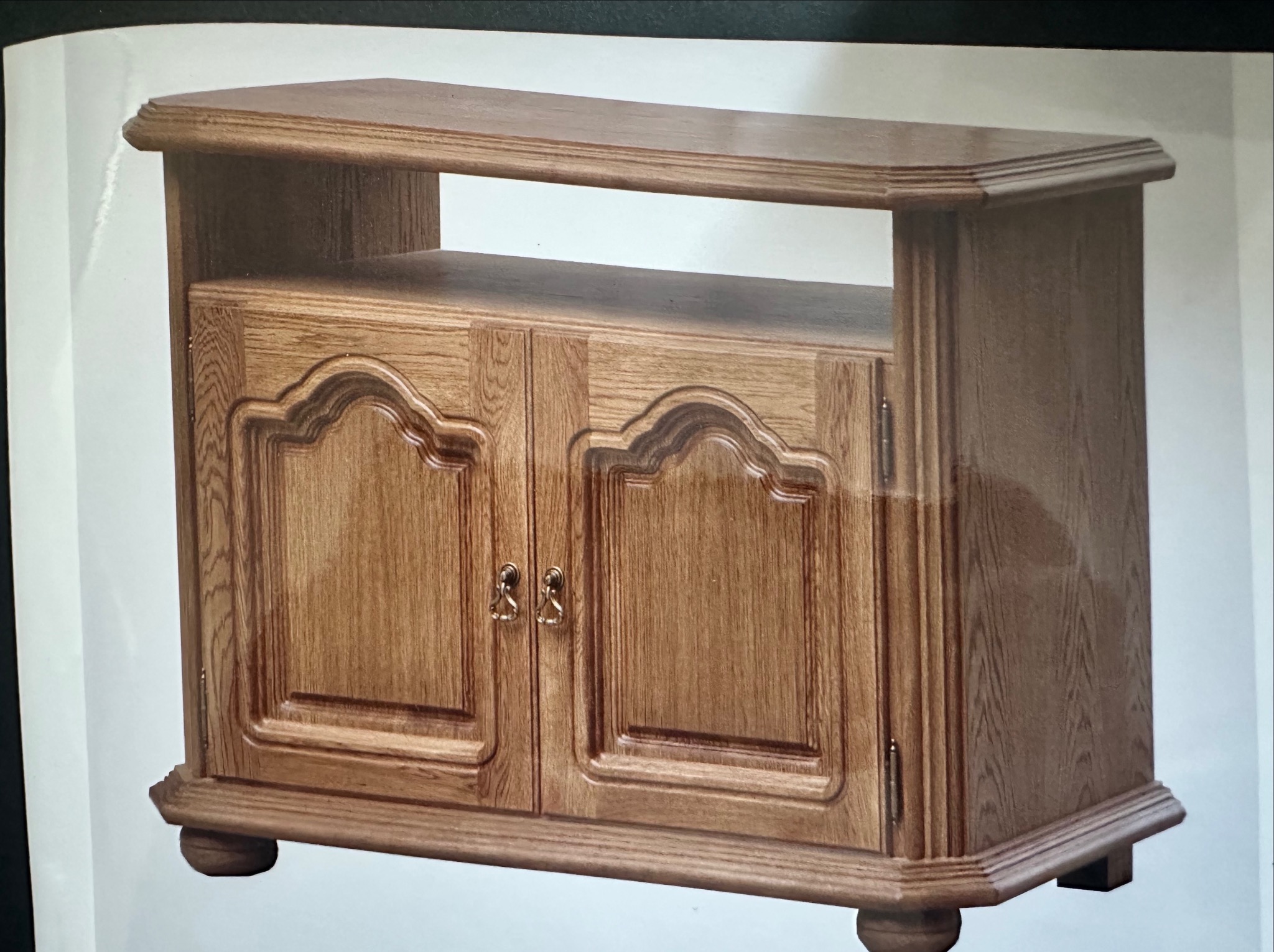 Drewniana szafka RTV z dwoma drzwiczkami i otwartą półką, wykończona w ciepłym odcieniu dębu, z dekoracyjnymi frezowaniami i okrągłymi nóżkami.