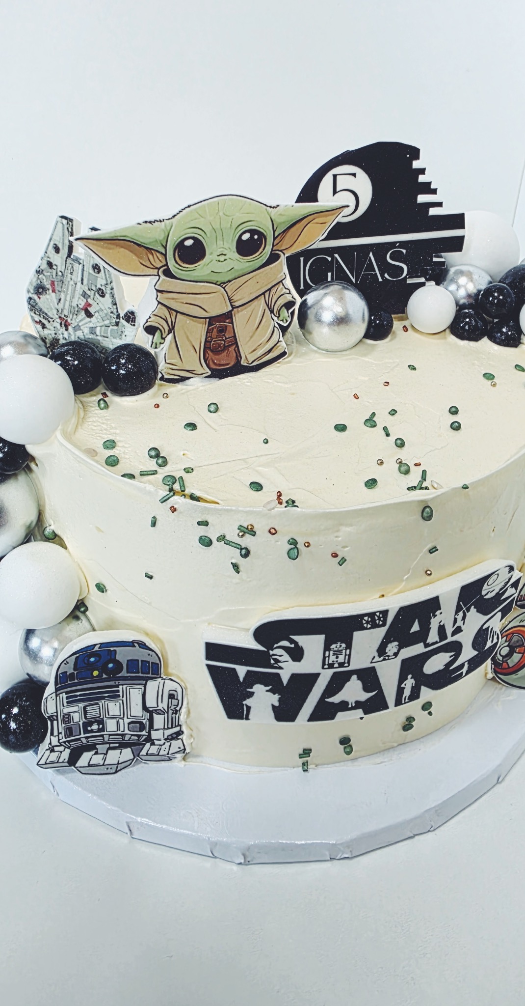Tort z motywem Star Wars, dekorowany figurką Baby Yoda i napisem 'Star Wars', posypany zielonymi drobinkami, z okazji 5 urodzin Ignasia.