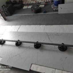 Stol-Lux - Płyty imitujące marmur z przyssawkami do przenoszenia, przygotowane do montażu, widoczne narzędzia i materiały budowlane w tle.