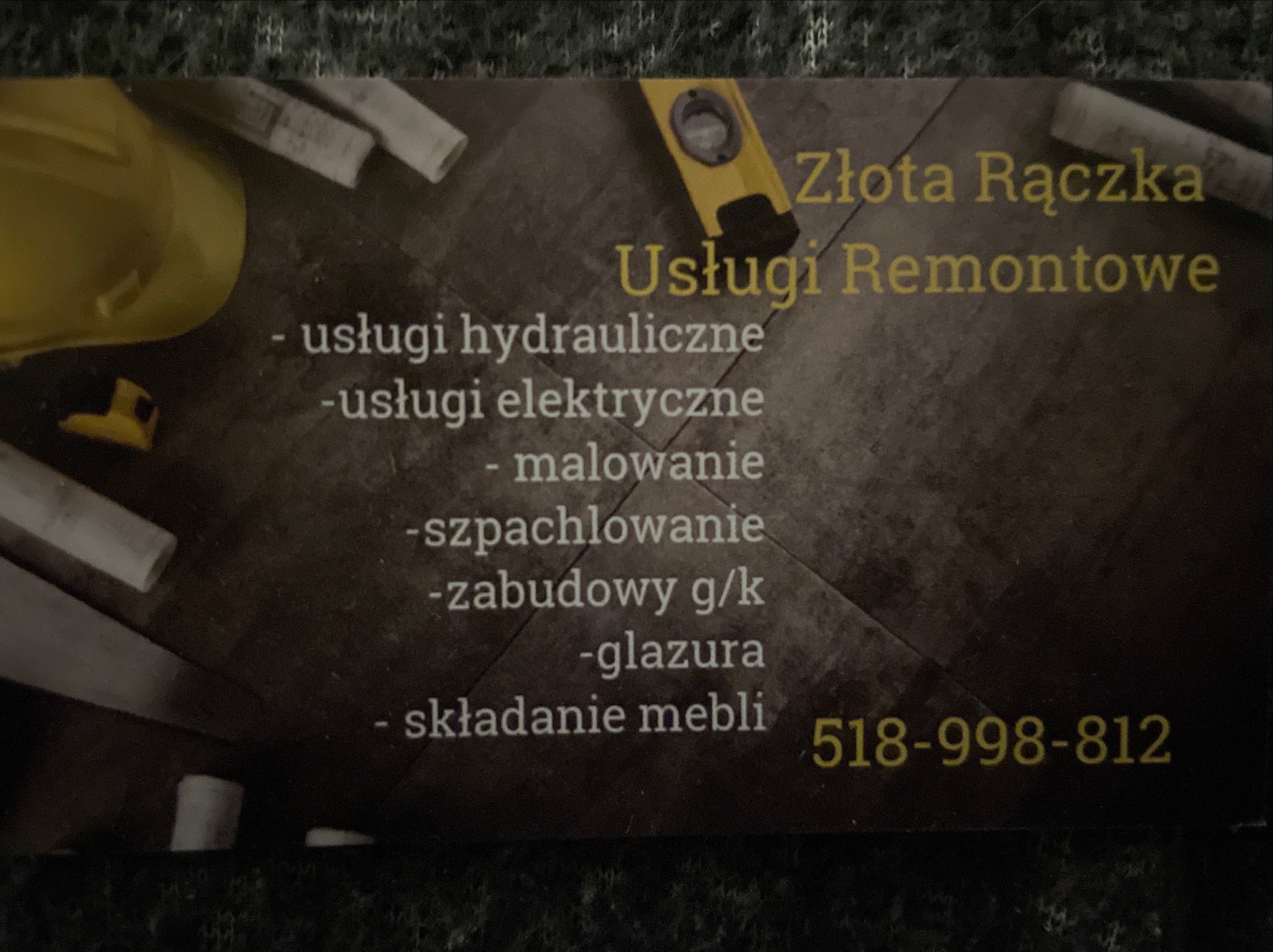 Wizytówka firmy remontowej 'Złota Rączka' z numerem telefonu, oferującej usługi hydrauliczne, elektryczne, malowanie, szpachlowanie, zabudowy g/k, glazurę i składanie mebli, otoczona kaskiem...