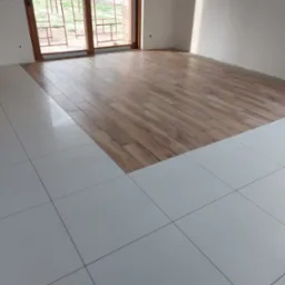 Układanie podłogi: połączenie białych, kwadratowych płytek i paneli imitujących drewno w jasnym wnętrzu z dużym oknem balkonowym.