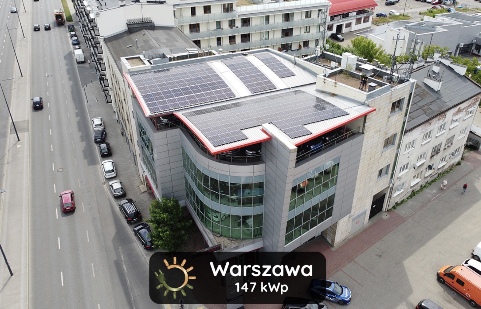 Widok z góry na budynek biurowy w Warszawie z instalacją paneli słonecznych na dachu i na zadaszeniu parkingu, moc instalacji 147 kWp.