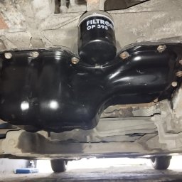 Michał Sobczyk - Czarna miska olejowa z nowym filtrem Filtron OP 595, widok od spodu pojazdu. Świeżo wymieniony olej, czyste elementy podwozia. Detal z warsztatu.