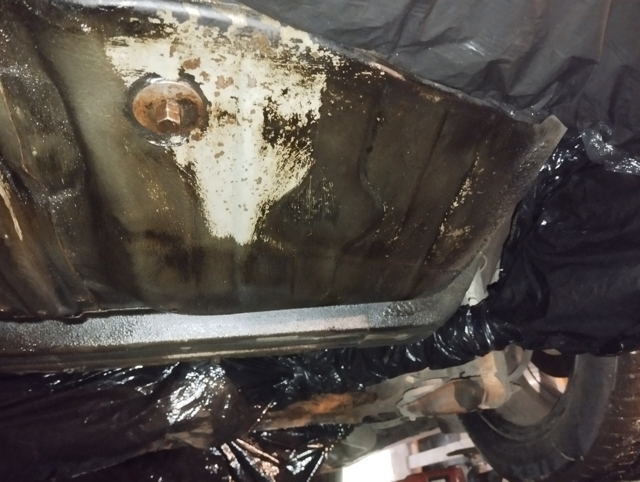 Podwozie auta po konserwacji antykorozyjnej w Świętochłowicach. Widoczne zabezpieczone elementy i świeża powłoka ochronna. Detal zardzewiałej śruby.