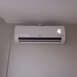 Biały klimatyzator LG Dual Inverter zamontowany na szarej ścianie z dekoracyjną listwą przypodłogową, widoczny wyświetlacz z temperaturą.