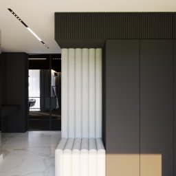 Katarzyna Pepke Zygalska Interiors - Nowoczesny przedpokój w ciemnej tonacji z marmurową posadzką, okrągłym lustrem z podświetleniem LED oraz tapicerowaną ścianą z siedziskiem.