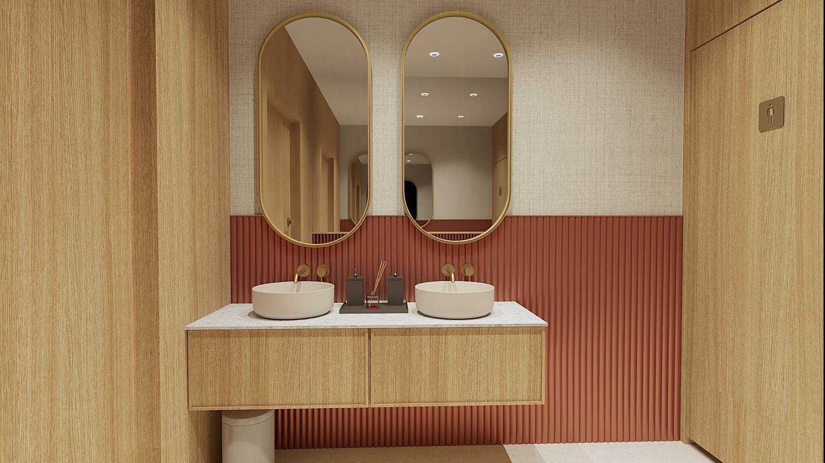 Nowoczesna łazienka z dwoma okrągłymi umywalkami nablatowymi, złotymi bateriami i owalnymi lustrami w złotych ramach, na tle ściany z pionowymi, pomarańczowymi panelami i tapety w odcieniach beżu.