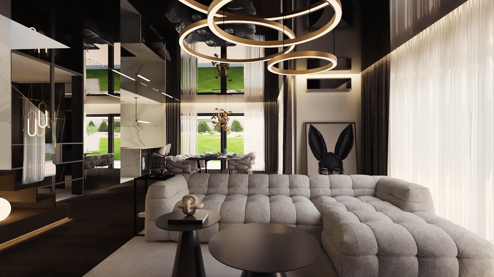 Nowoczesny salon z szarym, modułowym narożnikiem, okrągłym stolikiem kawowym i dekoracyjnym oświetleniem pierścieniowym. W tle widoczna jadalnia z widokiem na ogród i abstrakcyjny obraz z motywem...