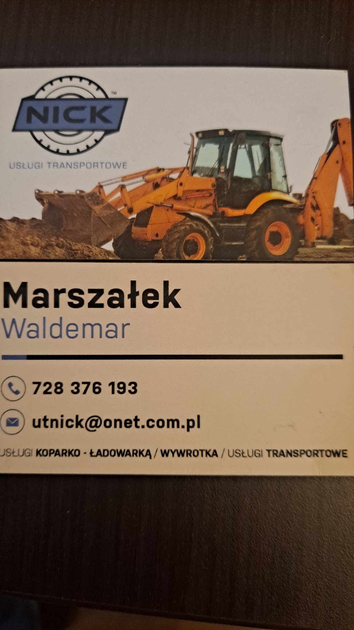Wizytówka firmy transportowej z ilustracją koparko-ładowarki, zawierająca logo, imię i nazwisko właściciela, numer telefonu oraz adres e-mail.