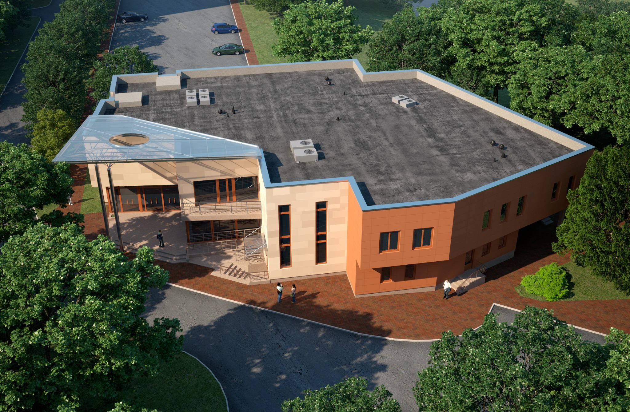 Widok z góry na nowoczesny budynek usługowy z płaskim dachem, szklanym zadaszeniem nad wejściem i elewacją w odcieniach beżu i pomarańczy, otoczony zielenią i parkingiem z kilkoma samochodami.