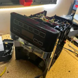 Rozmontowany ekspres do kawy marki Bosch VeroAroma na warsztatowym stole, widoczne wnętrze z kablami i elementami elektronicznymi, obok narzędzia.