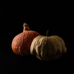 DUALART_PHOTOGRAPHY - Dwie dynie: pomarańczowa o chropowatej skórce i zielonkawa o gładkiej, na czarnym tle, w minimalistycznym ujęciu.