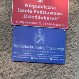 Tablica informacyjna: Kancelaria Radcy Prawnego Łukasz Rykowski w Szczecinie, adres al. Wyzwolenia 70. Nad tablicą szkoły podstawowej.
