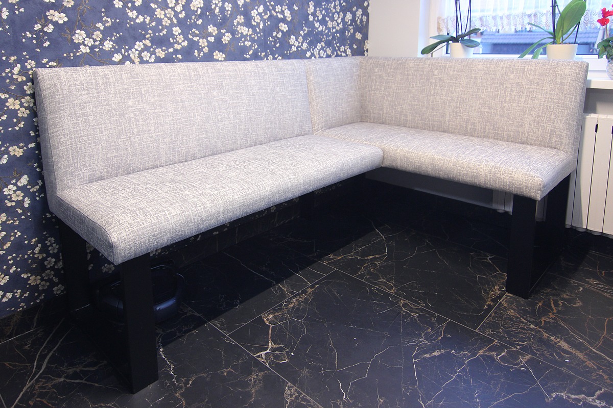 Szary narożnik kuchenny z tapicerowanym siedziskiem i oparciem, na tle ciemnej marmurowej podłogi i ściany w kwiatowy wzór.