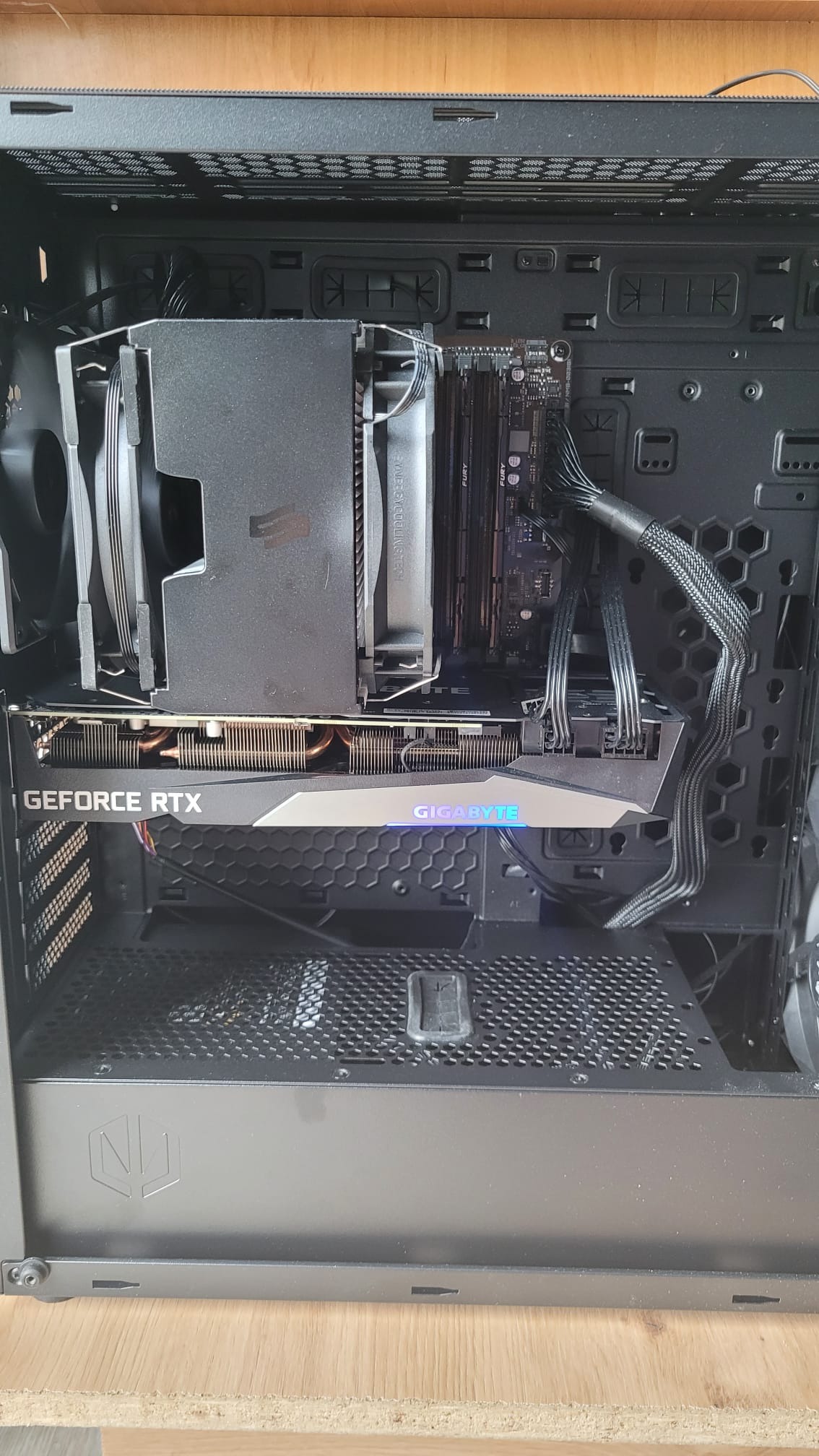 Wnętrze obudowy komputera stacjonarnego z zamontowaną kartą graficzną Gigabyte GeForce RTX i chłodzeniem procesora SilentiumPC Fera 5, widoczne przewody zasilające.