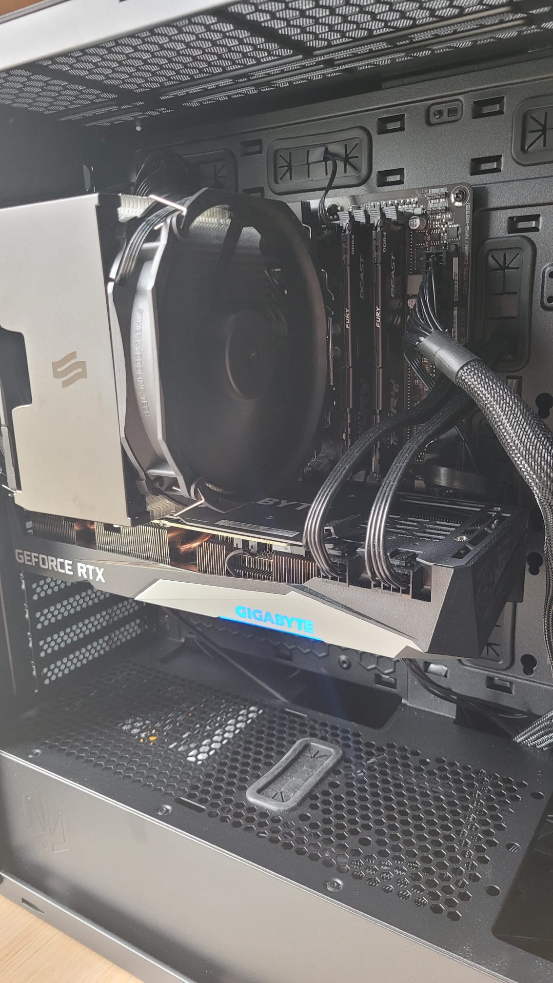 Wnętrze obudowy komputera stacjonarnego z zamontowaną kartą graficzną GeForce RTX z podświetlanym logo Gigabyte, chłodzeniem procesora z wentylatorem i pamięcią RAM Fury Beast DDR4.