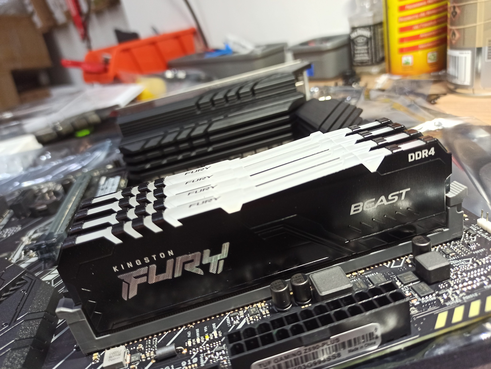 Moduł pamięci RAM Kingston Fury Beast DDR4 zainstalowany na płycie głównej komputera, widoczne elementy płyty głównej i radiator drugiego modułu RAM w tle, na stole warsztatowym.