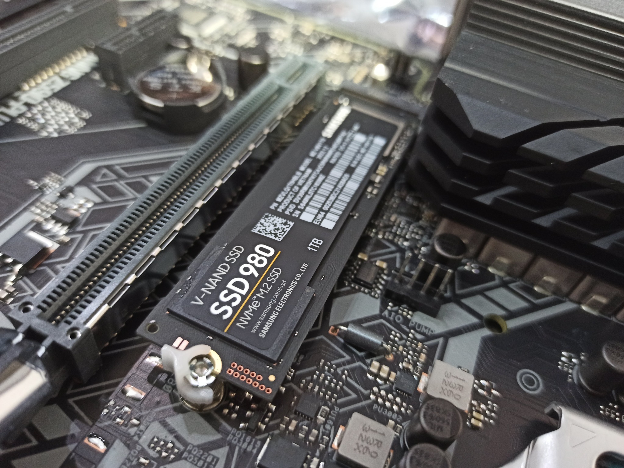 Dysk SSD Samsung 980 NVMe M.2 o pojemności 1TB, zainstalowany na płycie głównej komputera w Limanowej, widoczny z bliska pod kątem, obok slotu pamięci RAM.