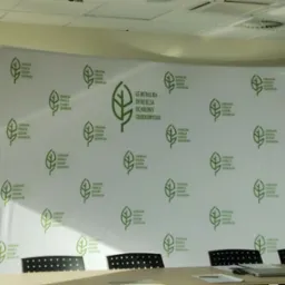 Ścianka reklamowa z logo Generalnej Dyrekcji Ochrony Środowiska w sali konferencyjnej, widok zza stołu.