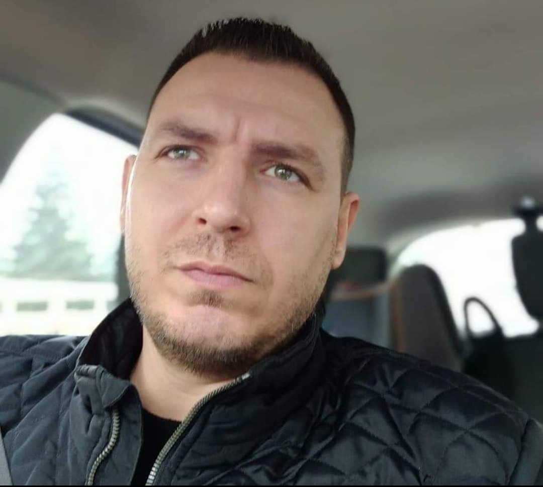 Mężczyzna w czarnej kurtce siedzący w samochodzie, prawdopodobnie w drodze do klienta.