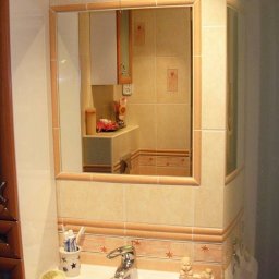 3D HOUSE - Umywalka z baterią i akcesoriami łazienkowymi, widok w lustrze odbija fragment blatu i szafki z dekoracjami, beżowe płytki z motywem gwiazdek na ścianach.