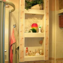 Narożna półka w łazience, wyłożona beżowymi płytkami z motywem gwiazdek, eksponująca dekoracje i kosmetyki na trzech poziomach, z oświetleniem punktowym na górze i widoczną kabiną prysznicową po...