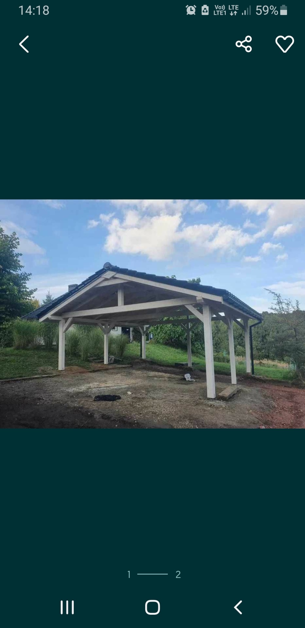 Zadaszenie w ogrodzie z białymi słupami i grafitowym dachem, widoczne z zewnątrz na tle zieleni i błękitnego nieba z chmurami.