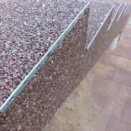 Zaczarowany kamyk - Schody zewnętrzne wykończone brązowym kamieniem otoczakowym, z metalową listwą krawędziową, widoczne z bliska pod kątem.