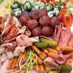 FAMILY - SERVICE YANA ANDRIUSHCHENKO - Bogato zaopatrzona deska serów, wędlin i owoców: kulki serowe z ziołami i czarnuszką, czerwone winogrona, plastry truskawek, szynka parmeńska, salami, kabanosy, pikle, cebulki marynowane i świeże...