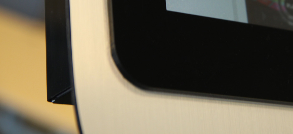 Fragment infokiosku z czarną ramką i ekranem dotykowym, widoczny z bliskiej perspektywy.