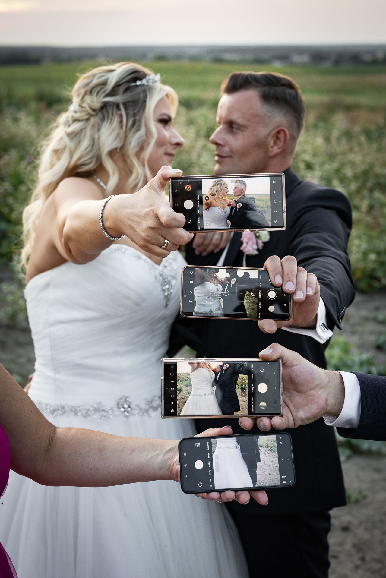 Para młoda w plenerze, sfotografowana przez kilka telefonów komórkowych, tworząc efekt zdjęcia w zdjęciu.