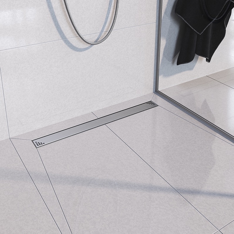 Nowoczesna łazienka z liniowym odpływem prysznicowym w posadzce z jasnych, kwadratowych płytek, widoczny fragment kabiny prysznicowej i słuchawka prysznicowa.