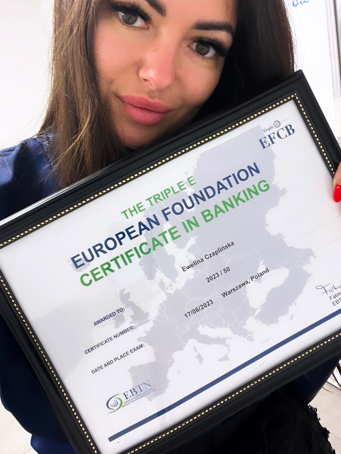 Kobieta trzyma w ramce certyfikat Europejskiej Fundacji Bankowej, uśmiechając się do kamery. Certyfikat z datą 17/06/2023 dla Eweliny Czaplińskiej z Warszawy.