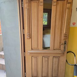 Darfloor - Otwarta, drewniana, ozdobna brama garażowa z widocznym wnętrzem budynku i grzejnikiem; po prawej stronie gaśnica.