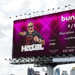 AUKCJE I SOCIAL MEDIA KAROL LASER - Billboard reklamowy klubu Bunny Club & Bowling z wizerunkiem DJ Hazela na tle miejskiej zabudowy, promujący wydarzenie 9/10 'Największa bania w Polsce!'