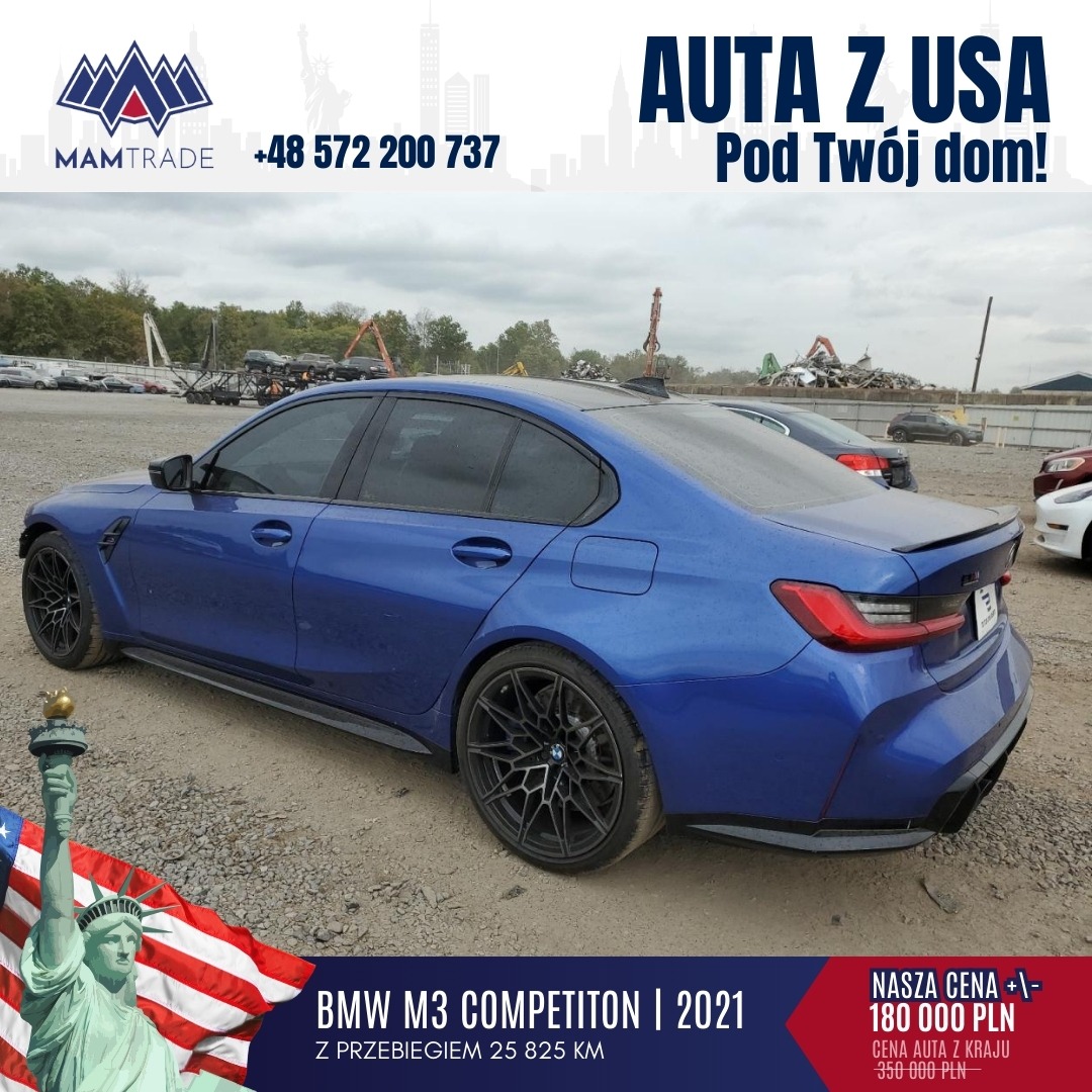 Niebieski BMW M3 Competition z 2021 roku, importowany z USA, zaparkowany na żwirowym placu z widocznym złomowiskiem w tle, flaga USA i Statua Wolności w lewym dolnym rogu.