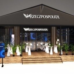 Sztuka Drewna Tworzymy z Pasją - Wizualizacja stoiska targowego z drewnianym podestem, czarną konstrukcją i logo 'Rzeczpospolita', wyposażonego w małe stoliki i rośliny doniczkowe.