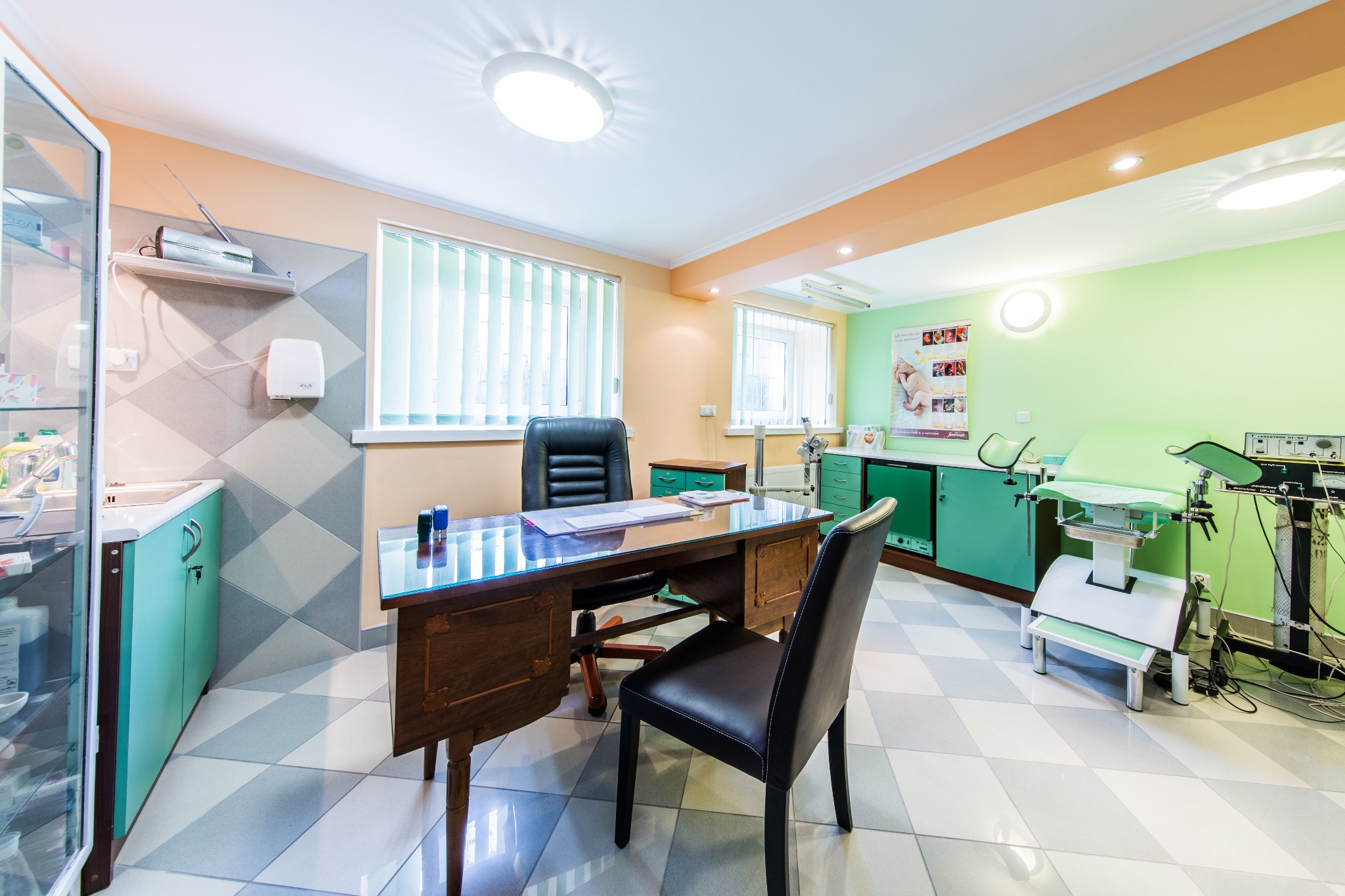 Jasny gabinet lekarski z biurkiem, fotelem, kozetką i aparaturą medyczną, ściany w odcieniach zieleni i beżu, podłoga w biało-szarą szachownicę.
