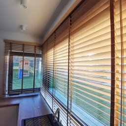 JBM Jakub Bizoń - Drewniane żaluzje poziome w kuchni, widok na ogród przez okno, czarny zlew z ociekaczem.