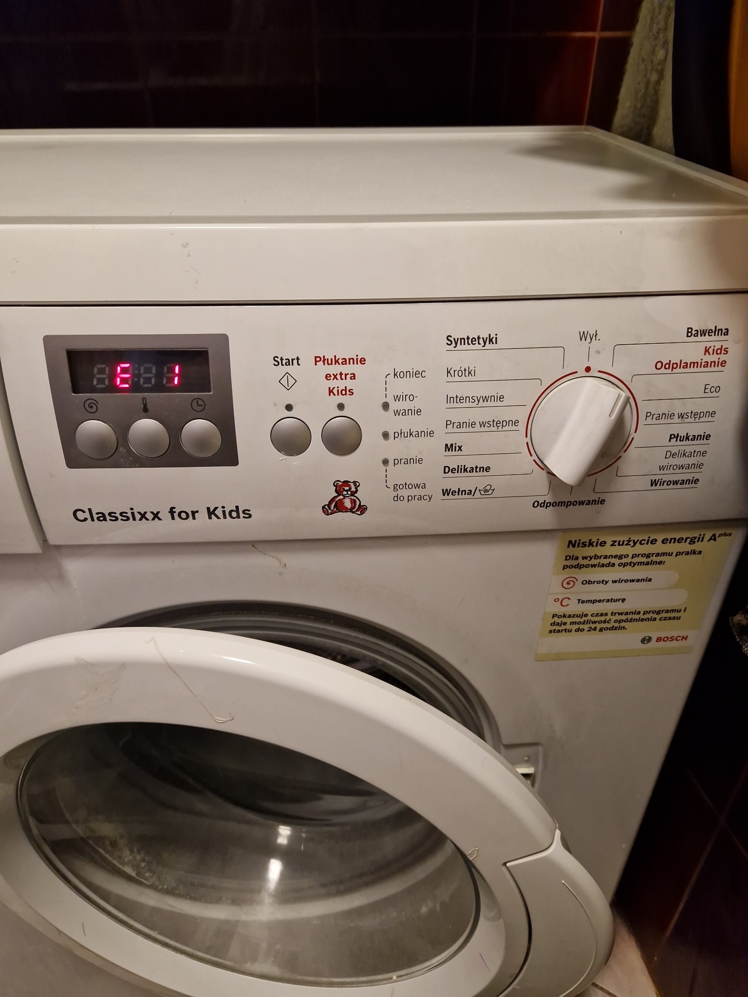 Pralka Bosch Classixx for Kids z otwartymi drzwiczkami, widoczny panel sterowania z ustawionym programem i naklejką informującą o niskim zużyciu energii.