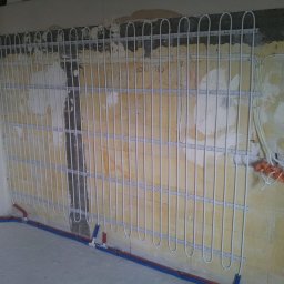 Instalacje sanitarne serwis urządzeń grzewczych - Montaż rur ogrzewania podłogowego na ścianie w trakcie realizacji w Warszawie, widoczne mocowania i fragment instalacji hydraulicznej.