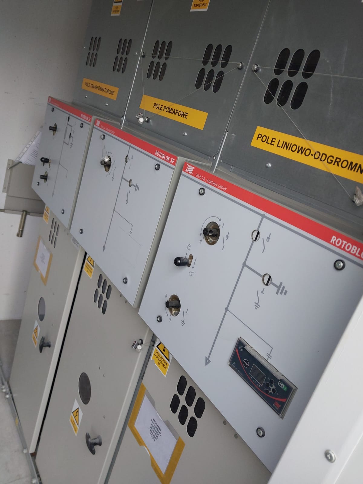 Rozdzielnica elektryczna niskiego napięcia typu ROTOBLOK SF z widocznymi polami transformatorowym, pomiarowym i liniowo-odgromowym, zawierająca schematy elektryczne i ostrzeżenia.